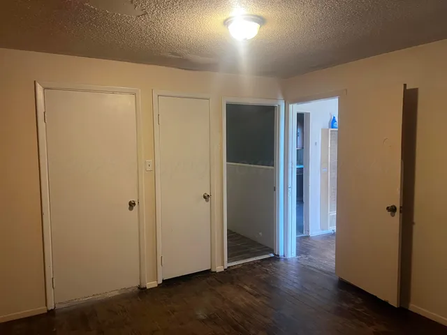 an empty room with wooden floor & closet area