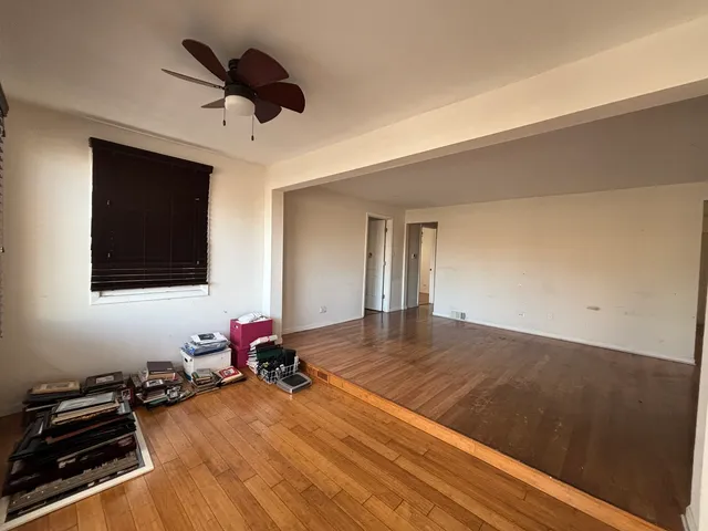 a room with wooden floor and ceiling fan