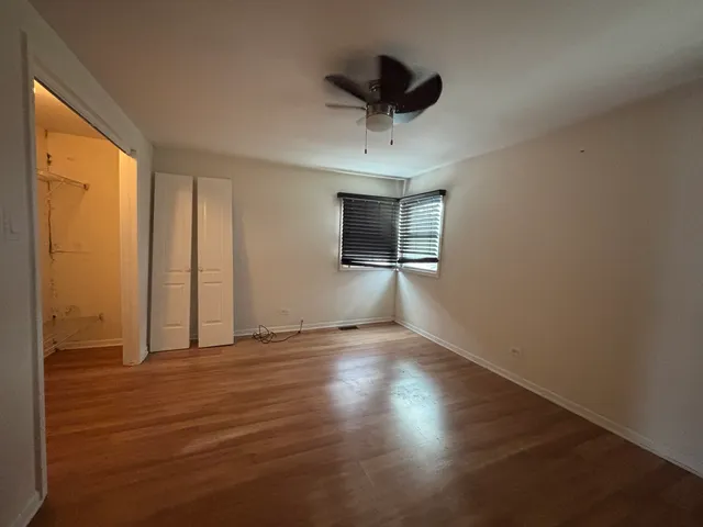 a view of empty room with wooden floor and fan