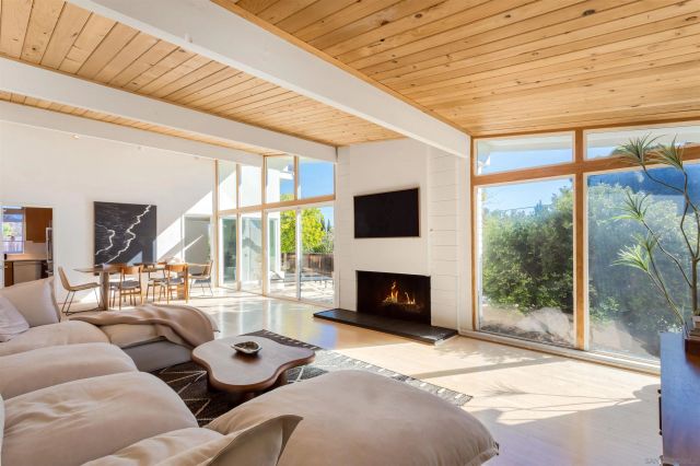 a living room with furniture a fireplace and a floor to ceiling window