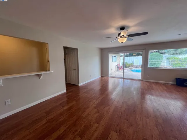 a view of an empty room with a window and wooden floor