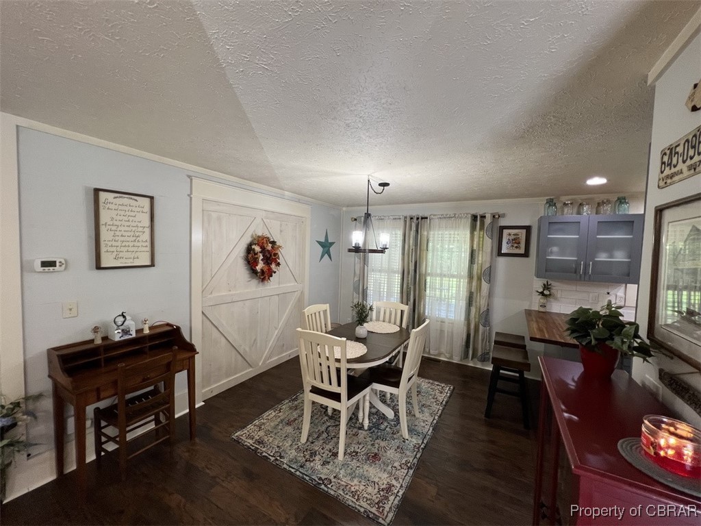 102 Mechams Cove Road Topping, VA 23169 - Photo 18 of 40 Dining space with a textured ceiling, dark wood-style flooring, healthy amount of natural light, and a chandelier