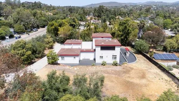 an aerial view of residential houses with outdoor space and trees