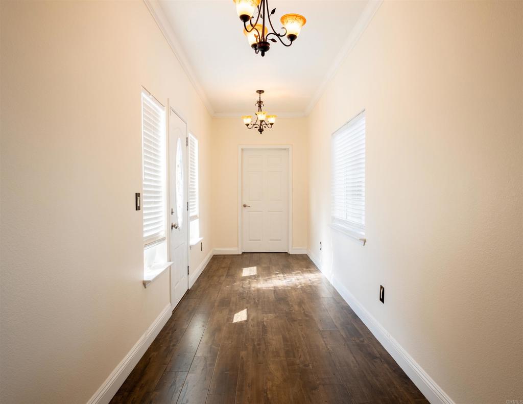 441 Rancho Santa Fe Road Encinitas, CA 92024 - Photo 10 of 17 a view of a hallway with wooden floor and a chandelier