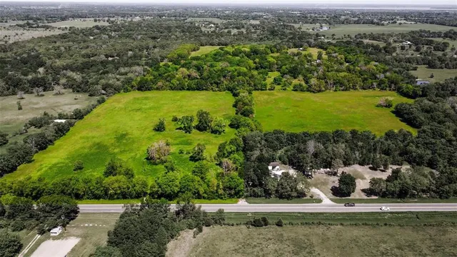 an aerial view of a residential houses with outdoor space and trees