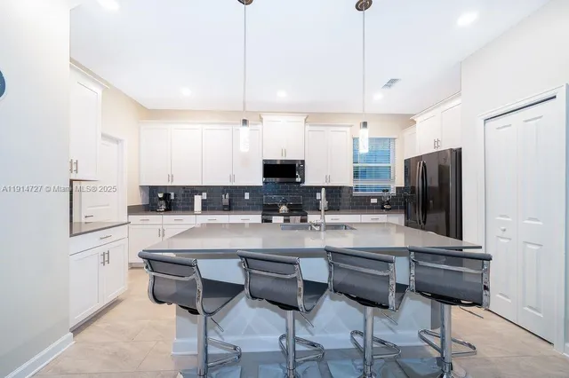 a kitchen with stainless steel appliances granite countertop a sink a stove a refrigerator and island with wooden floor