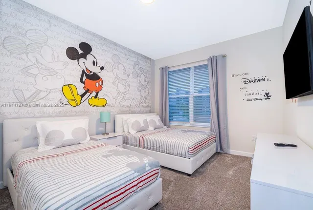 a bedroom with 2 bed and a flat screen tv