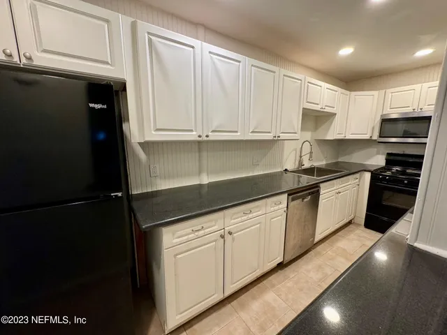 a kitchen with granite countertop a refrigerator sink and cabinets
