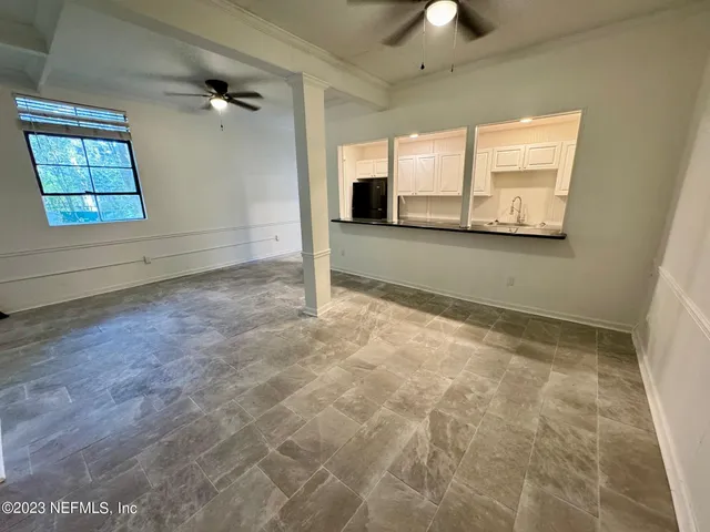 an empty room with windows and ceiling fan