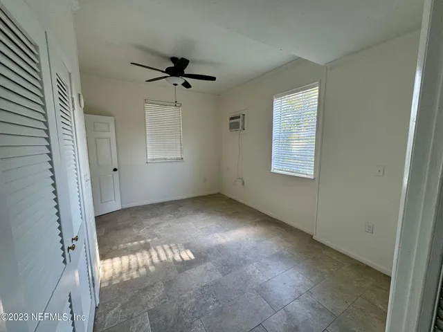 an empty room with windows and fan