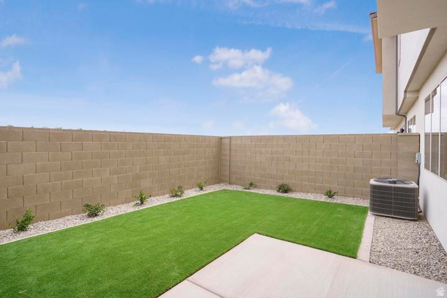 990 Manen Street Washington, UT 84780 - Photo 36 of 43 Rear yard featuring a green turf area, concrete patio, gravel borders, and a block perimeter wall