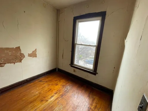 a view of an empty room with wooden floor and a window
