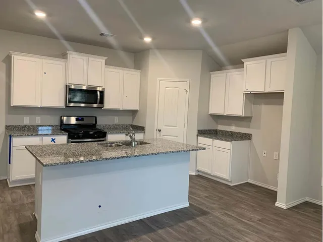 a kitchen with granite countertop white cabinets and stainless steel appliances