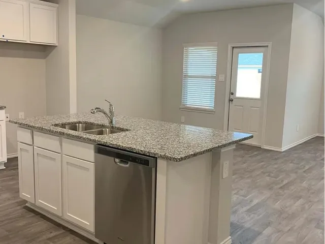 a kitchen with granite countertop a sink and cabinets