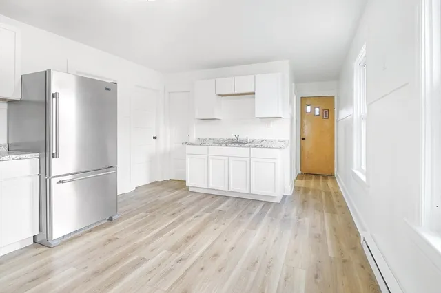 a kitchen with white cabinets and wooden floors