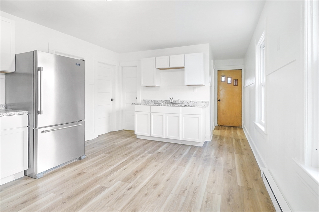 12 Temple Street Holyoke, MA 01040 - Photo 15 of 36 a kitchen with white cabinets and wooden floors