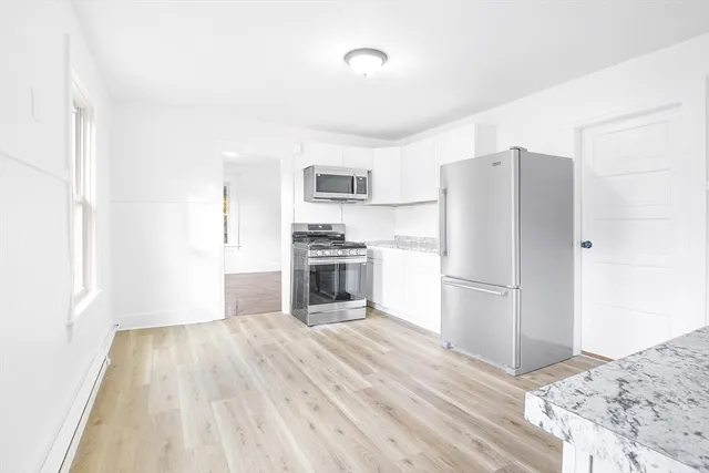 a kitchen with a refrigerator a stove and a sink with wooden floor
