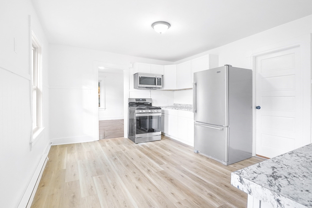 12 Temple Street Holyoke, MA 01040 - Photo 17 of 36 a kitchen with a refrigerator a stove and a sink with wooden floor