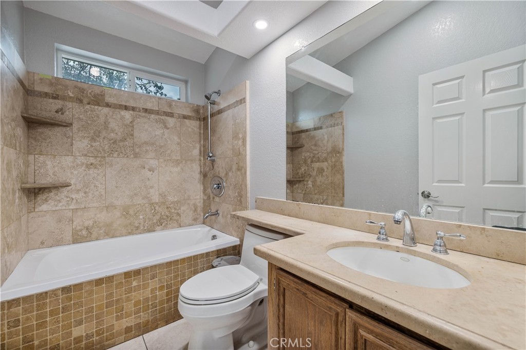15608 Tierra Rejada Road Moorpark, CA 93021 - Photo 17 of 34 a bathroom with a granite countertop sink a toilet a mirror and bathtub