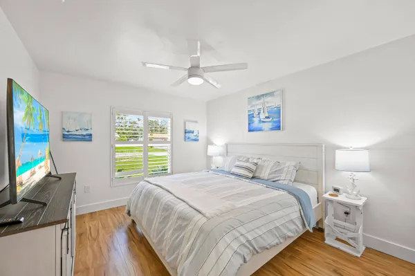a bedroom with a bed a computer on the desk and a dresser next to a window