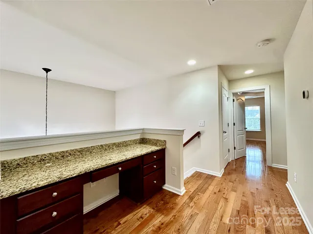 a spacious bathroom with a granite countertop sink and a wooden floor