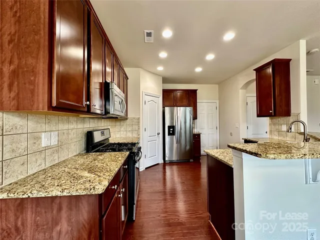 a kitchen with stainless steel appliances granite countertop a sink stove and refrigerator