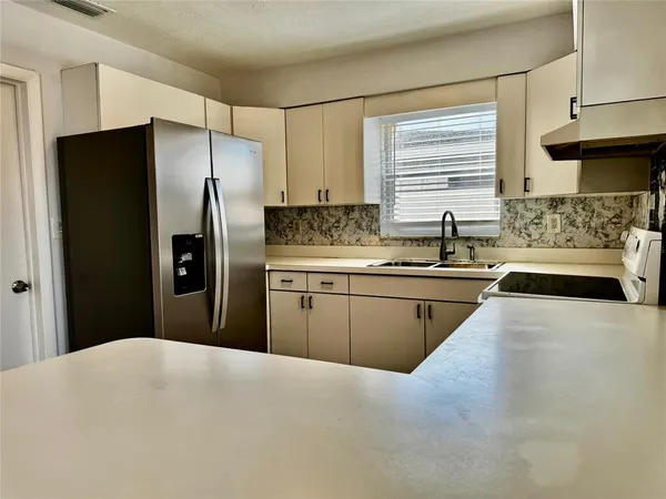 a kitchen with a sink a refrigerator and a stove top oven