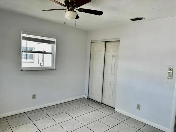 a view of an empty room with window and chandelier fan