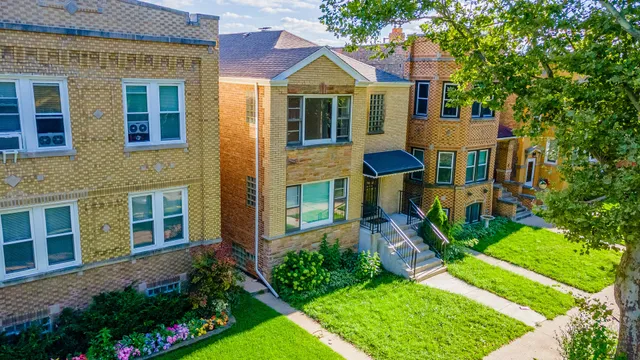 a front view of a house with a yard and potted plants