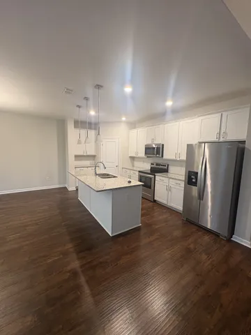 a large kitchen with a center island wooden floor stainless steel appliances and cabinets