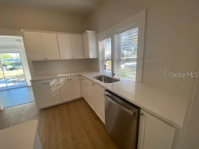 a white kitchen with a sink a window and appliances