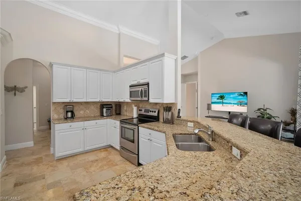 a large kitchen with a stove a sink dishwasher and a microwave oven with white cabinets