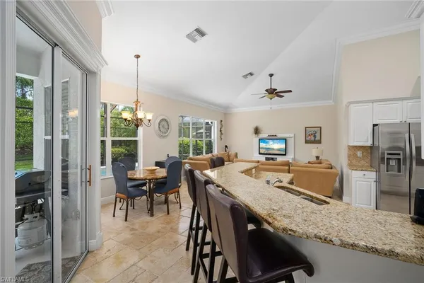 a dining hall with stainless steel appliances granite countertop a dining table and chairs