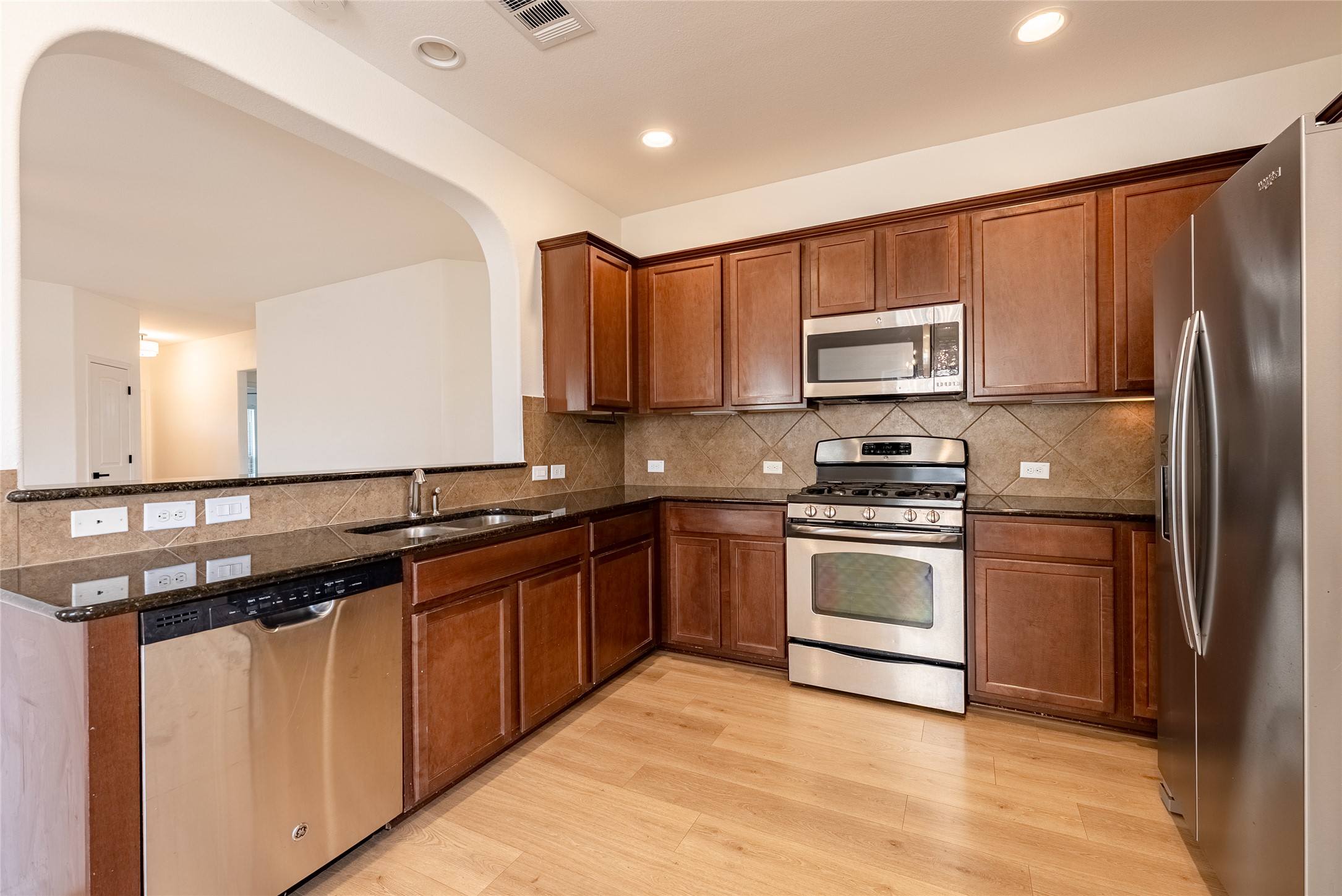 1437 April Meadows Loop Georgetown, TX 78626 - Photo 10 of 31 a kitchen with stainless steel appliances granite countertop a refrigerator a sink dishwasher a stove and white cabinets with wooden floor