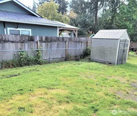 a view of backyard with small cabin and wooden fence