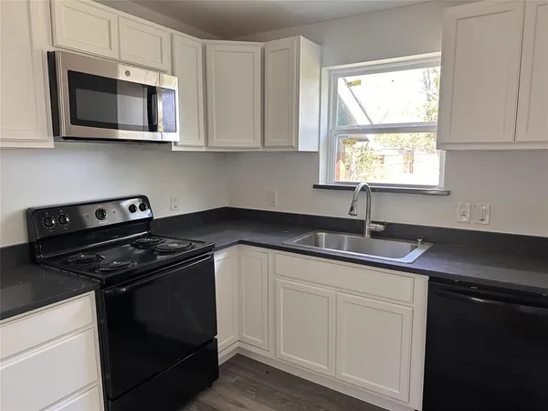 a kitchen with stainless steel appliances granite countertop white cabinets granite counter tops and a window