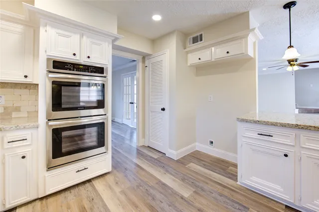 an empty room with windows and chandelier fan