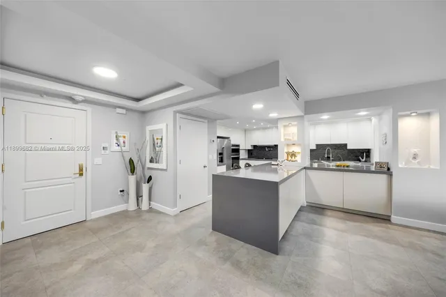a large white kitchen with white cabinets and stainless steel appliances