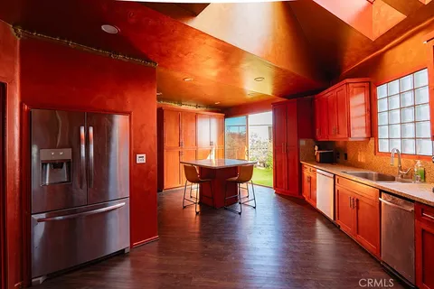 a kitchen with stainless steel appliances granite countertop a refrigerator a sink dishwasher a stove and white countertops with wooden floor