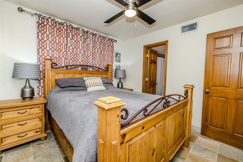 1655 Cedar Crest Loop, Unit E7 Graford, TX 76449 - Photo 15 of 35 a bedroom with a bed and a chandelier