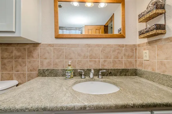 a bathroom with a granite countertop sink toilet and a mirror