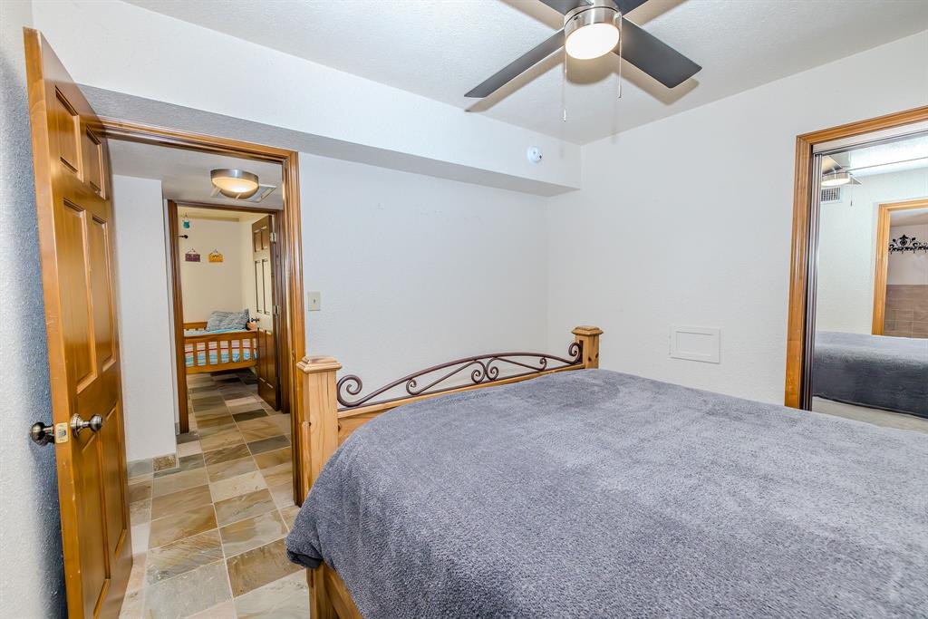 1655 Cedar Crest Loop, Unit E7 Graford, TX 76449 - Photo 19 of 35 a bedroom with a bed and a chandelier