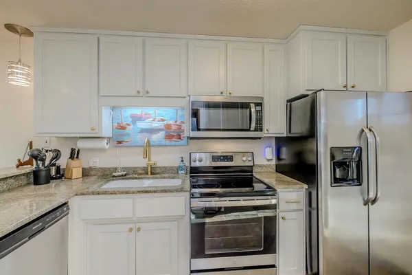 a kitchen with granite countertop white cabinets and stainless steel appliances