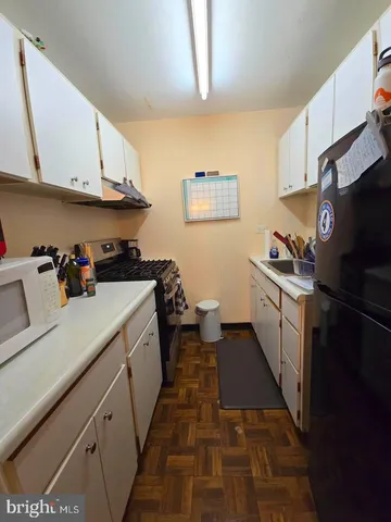 a kitchen with a sink dishwasher stove and white cabinets