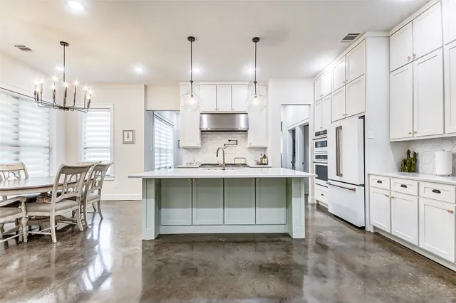 a kitchen with kitchen island granite countertop a sink cabinets and stainless steel appliances