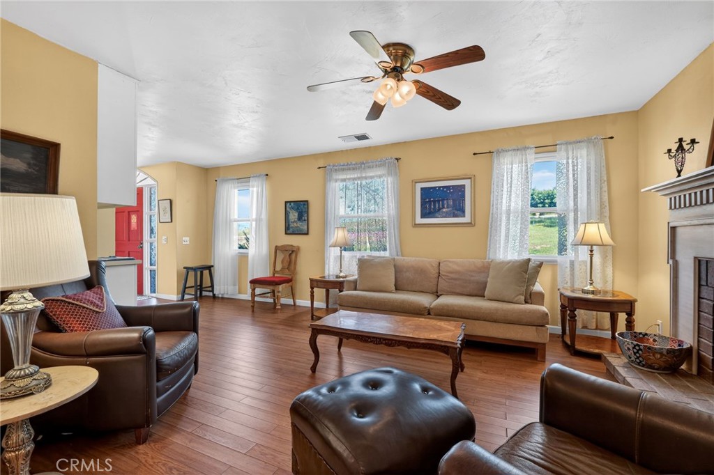 10079 West Lilac Road Escondido, CA 92026 - Photo 9 of 50 a living room with furniture a ceiling fan a fireplace and a window