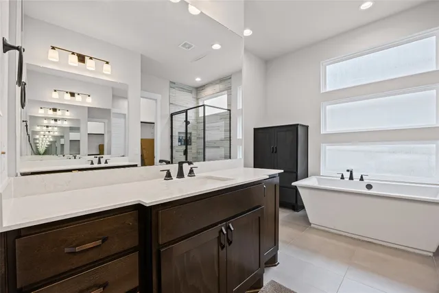 a bathroom with a double vanity sink mirror and bathtub