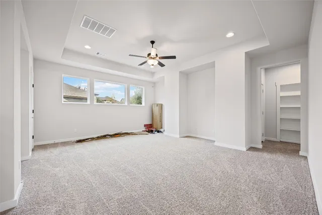an empty room with chandelier fan and windows