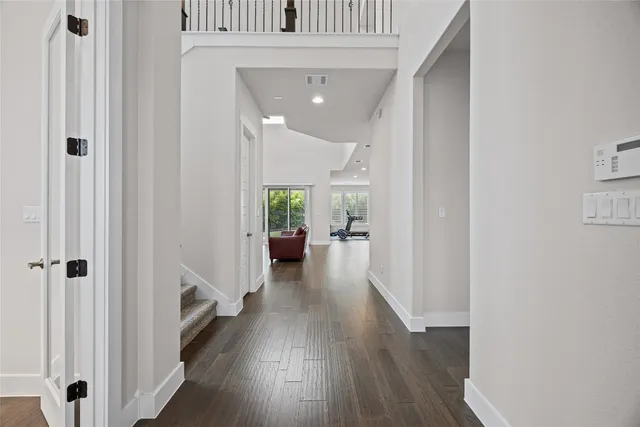 a view of a hallway with wooden floor and a bathroom