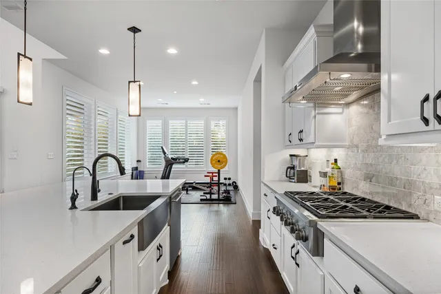a kitchen with kitchen island stainless steel appliances a sink a stove and a wooden floors